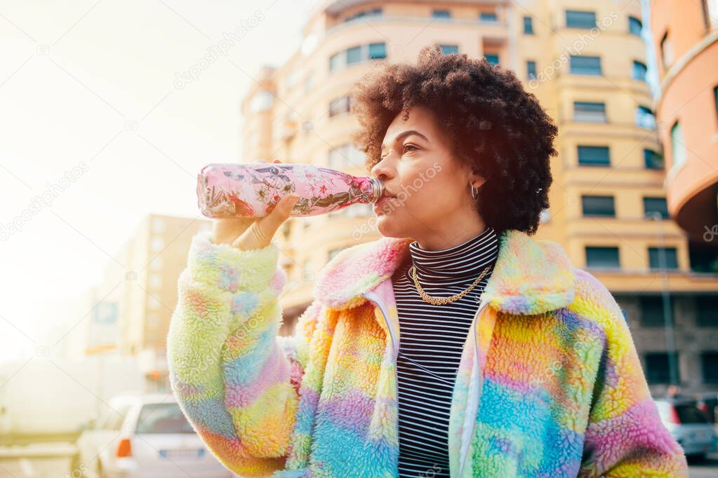 Young beautiful multiethnic woman drinking from reusable stainless bottle - zero waste, plastic free, eco friendly concept