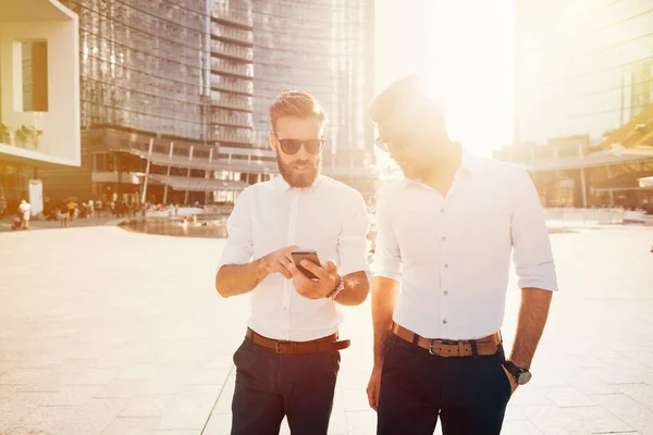 Two Young Businessmen Outdoor Back Light Walking Using Smartphone Vusiness — Stock Photo, Image