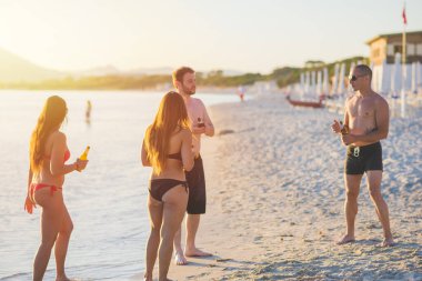 Sahilde bira içen etnik çeşitliliğe sahip genç bir grup. Kutlama, tatil, eğlence konsepti.