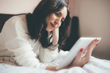 Yatakta yatan tablet kullanan genç ve güzel bir kadın video görüntüsü - karantina, teknoloji, iletişim konsepti