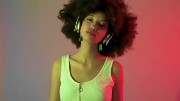 年轻美丽的多民族女性室内录音室 用耳机聆听着丰富多彩的背景音乐 娱乐和自由的概念 — 图库视频影像