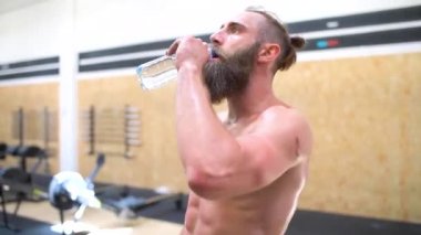 Spor salonundaki yakışıklı genç adam içme suyu içmekten, dinlenmekten, spor yapmaktan yorgun düşmüş.