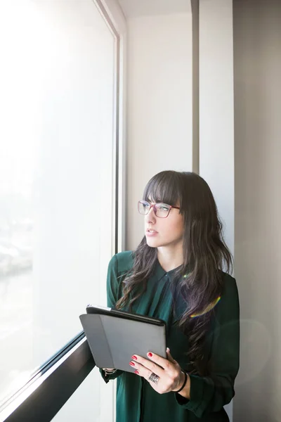 窓の近くに立つ若い美しい白人ビジネス女性屋内でタブレットを持ち上げる ビジネス 5Gテクノロジー 金融コンセプト — ストック写真