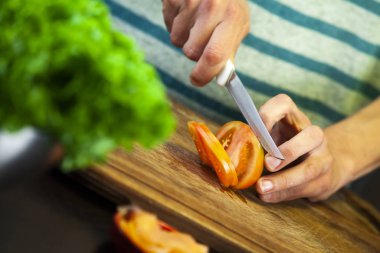 Kırmızı domatesi bıçakla kesen kız.