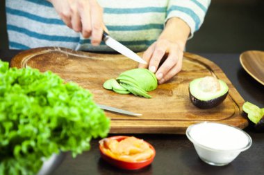 Karısı olgun bir avokadoyu dilimlere ayırıyor.