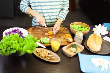 Mutfaktaki kız domatesleri kesiyor.
