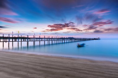 Bir deniz yüzeyi su ve gökyüzü hareket bulanıklaştırma efektleri ile woode bridge ile uzun pozlama ışık toplayan düşük.