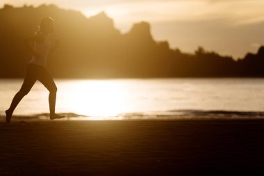 Woman running on the beach at sunrise. clipart