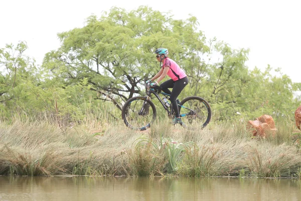 年轻女子骑山地自行车赛在大坝的边上 — 图库照片