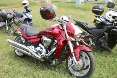 Yeşil çimenlerin üzerinde park edilmiş kırmızı Suzuki Boulevard M109r motosiklet