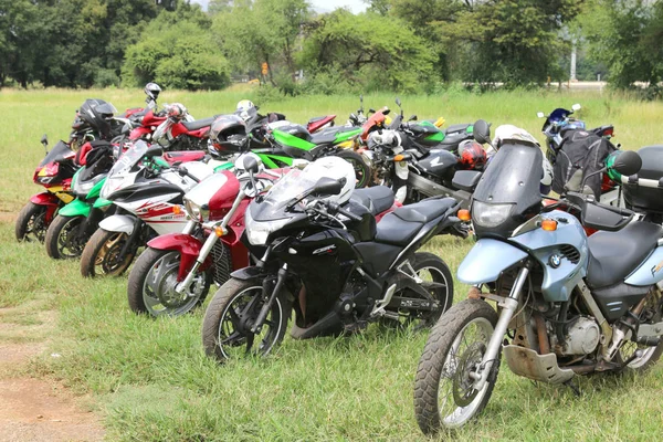 Fileiras de motocicletas coloridas estacionadas na grama verde — Fotografia de Stock
