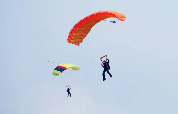 Twee parachutisten met kleurrijke chutes cirkelen in wachtrij voor landin — Stockfoto