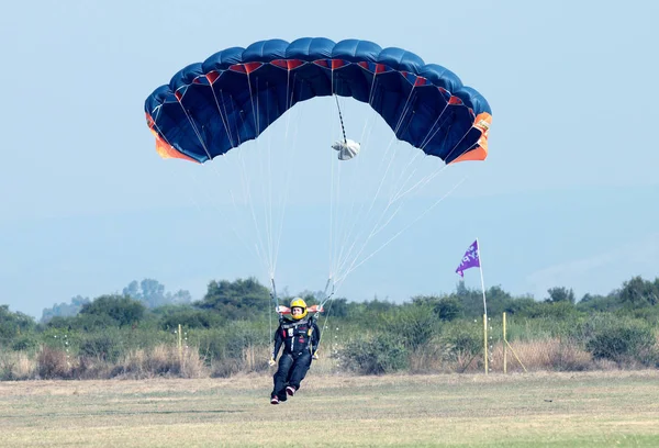 Paraquedismo feminino fazendo pouso seguro na grama com abrir brilhantemente — Fotografia de Stock