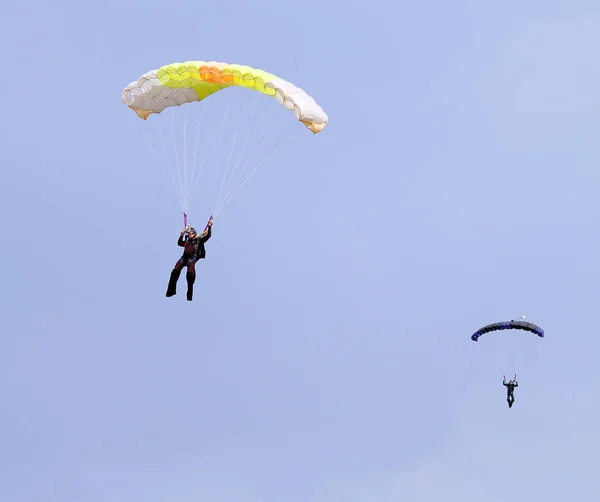 Zwei Fallschirmspringer mit bunten Rutschen nähern sich Landeplatz in — Stockfoto