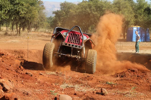 Carro vermelho subindo íngreme dugout chutando areia e poeira . — Fotografia de Stock