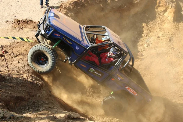 Voiture bleue alimentant la colline abrupte, bottant le sable et la poussière . — Photo