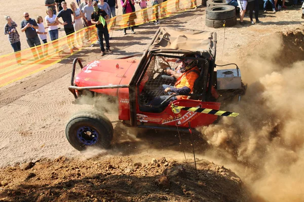 Spectators watching red car powering out of dugout — Stock Photo, Image