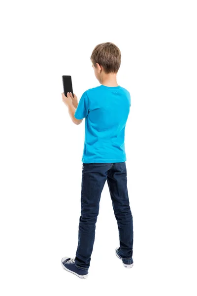 Rückansicht eines Jungen in T-Shirt und Jeans, der mit dem Handy spricht lizenzfreie Stockfotos