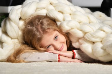 Young preety girl lying near under big handmade merino wool blan clipart