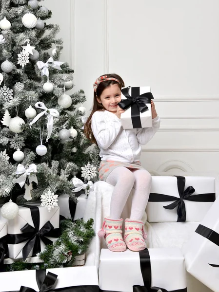 プレで飾られたクリスマス ツリーのそばに座って幸せな少女 — ストック写真