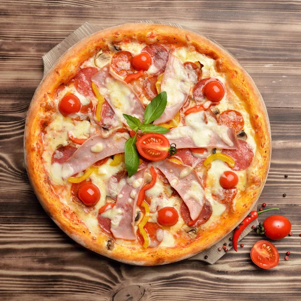 Pizza sabrosa entera grande caliente con jamón de tomates de tocino de queso derretido — Foto de Stock