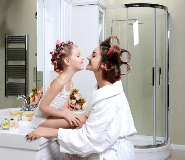 Fiatal anya és lánya a hajcsavaró, egy fürdő szoba, boldog mosolygó — Stock Fotó