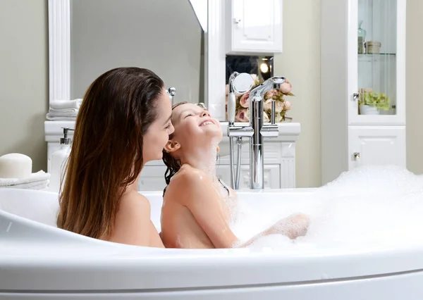 Genç anne ve kızı hu gülümseyerek mutlu bir banyo oynarken — Stok fotoğraf
