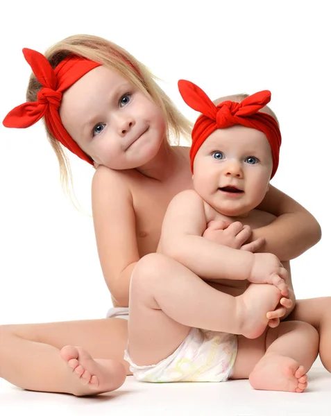 Schöne kleine Schwestern sitzen umarmt glücklich lächelnd im gleichen r — Stockfoto