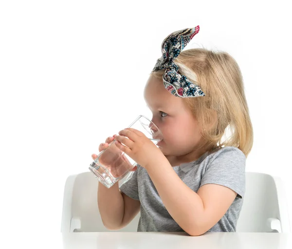Child baby girl sitting with glass of drinking water Royalty Free Stock Photos