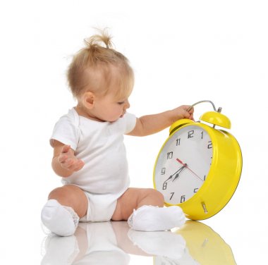 Büyük sarı alarm saat isolat ile oturan bebek çocuk kız çocuk