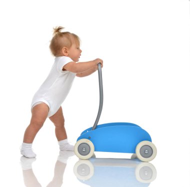 Küçük gülümseyen bebek kız yürümeye başlayan çocuk oyuncak walker ile ilk adımları yapmak
