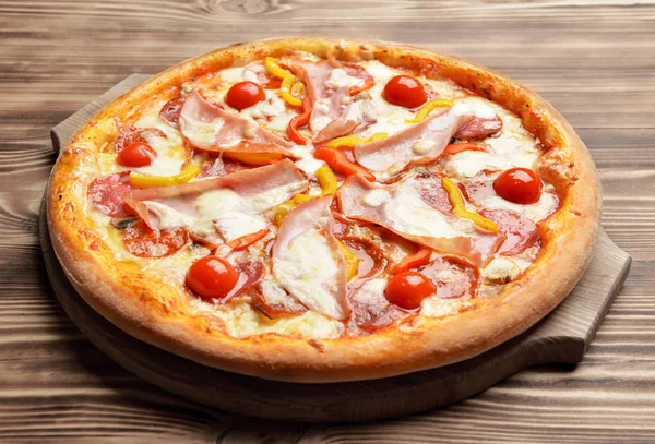 Pizza sabrosa entera grande caliente con queso derretido tomates pimentón de jamón — Foto de Stock