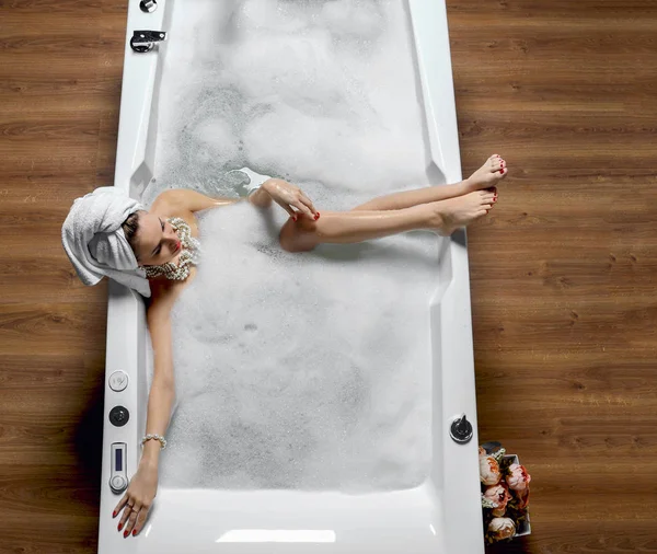 Wanita mode mewah dengan handuk besar lembut di pagi hari spa hotel berbaring di bak mandi — Stok Foto