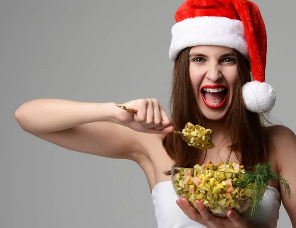 Donna in Natale cappello di Babbo Natale felice urlando mangiare insalata Olivier — Foto Stock