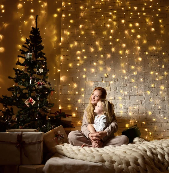 若い母親とクリスマス ツリーが魔法の新年のギフトのそばに座ってそびれた娘 — ストック写真