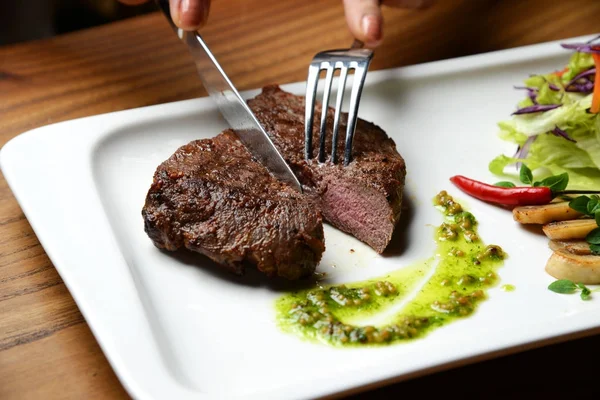 手は、グリーン ドレッシング ソース ピーマン マッシュルームとサラダとミディアムレアの牛肉ステーキします。 — ストック写真