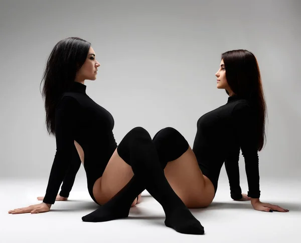 Dwa sportowe brunetka kobieta treningu ćwiczenia rozciągające razem w czarny atletyczna — Zdjęcie stockowe