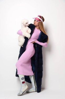 Pembe uzun bluz ve şapka holding beyaz kaniş köpek glamour kadında genç moda 