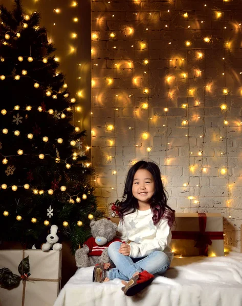 ゴールド パッチワーク ギフトで装飾されたゴールドのクリスマス ツリーの下に座ってアジア子供赤ちゃん女の子子供プレゼントします。 — ストック写真