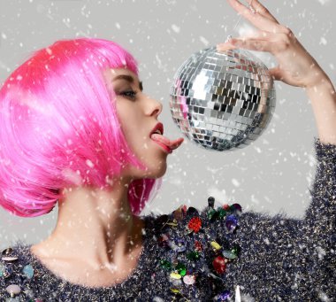 Şık pembe kanat Noel dekorasyon disko topu ile göz kırpıyor içinde genç güzel moda kadın portresi 