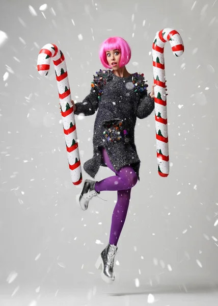 세련 된 핑크 날개와 모자에 젊은 아름 다운 패션 여자의 초상화 잡고 두 개의 큰 크리스마스 캔디 지팡이 — 스톡 사진