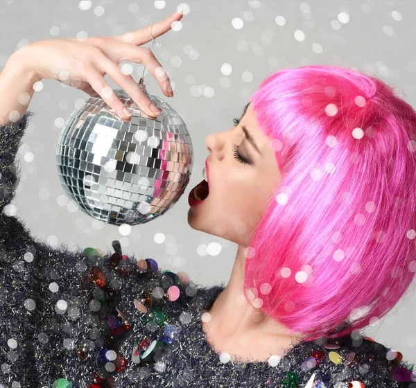 Portrait of young beautiful fashion woman in stylish pink wing winking with christmas decoration disco ball — Stock Photo, Image