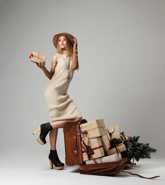 Vacker kvinna resenär i hatt med stora öppna läder retro väska full med nuvarande julklappar — Stockfoto