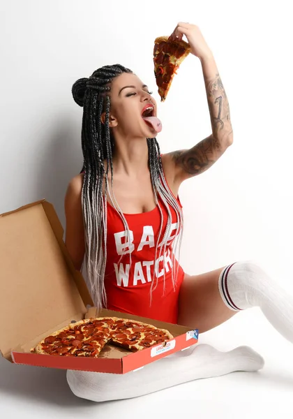 Jeune belle femme sexy dans un élégant gilet rouge et dreadlocks manger pizza pepperoni tranche — Photo