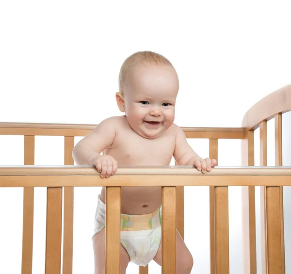Infant child baby girl in wooden bed looking down happy smiling — Stock Photo, Image