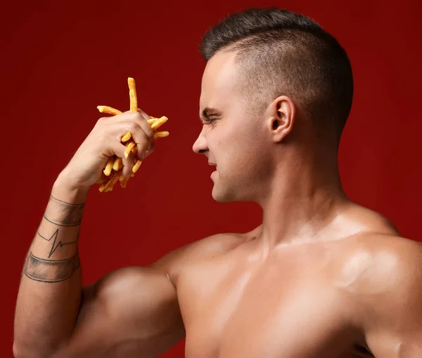 Strong muscular athlete men hold in hand french fries unhealthy junk fast food — Stock Photo, Image