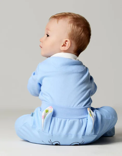 Niño bebé niño niño pequeño sentado en azul claro y verde y mirando a la esquina —  Fotos de Stock