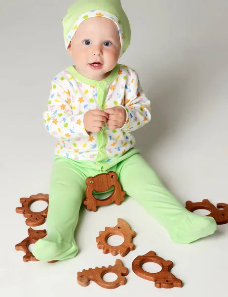 Bebek çocuk erkek bebek ışık yeşil vücutta oturan yürümeye başlayan çocuk ve ahşap teether oyuncak tutun — Stok fotoğraf