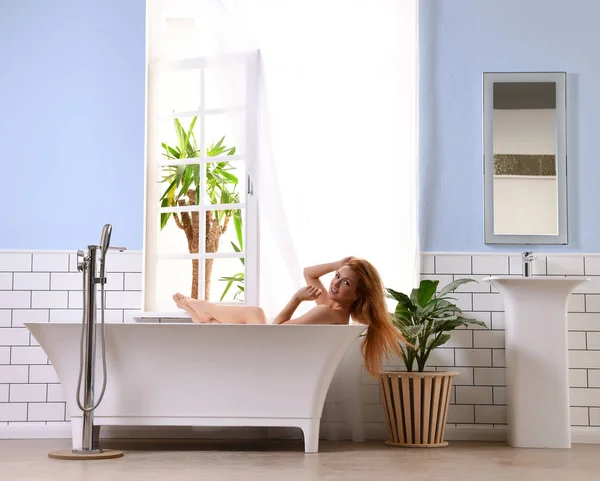 Açık banyo yakınındaki alarak banyo ve küvet içinde yatan genç güzel kadın — Stok fotoğraf