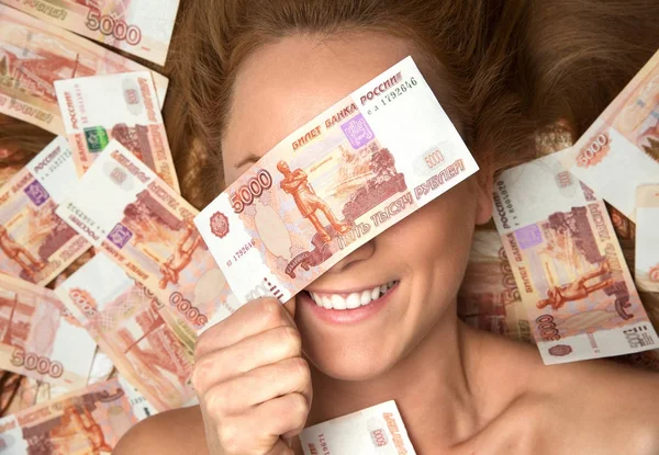 年轻女子躺在与许多现金钱5000俄罗斯卢布笔记密切的眼睛 — 图库照片
